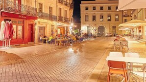 Eine Kopfsteinpflasterstraße mit Außenbestuhlung und einem Café.