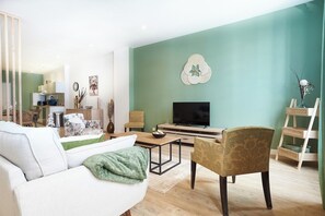 Uma sala de estar moderna com sofá, poltrona, mesa de centro, televisão e objetos decorativos.