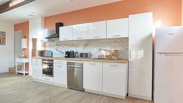 A modern kitchen with white cabinets, a stainless steel dishwasher, and a built-in oven.