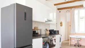 Eine moderne Küche mit einem Edelstahl-Kühlschrank, einer Waschmaschine und einem Essbereich mit Tisch und Stühlen.