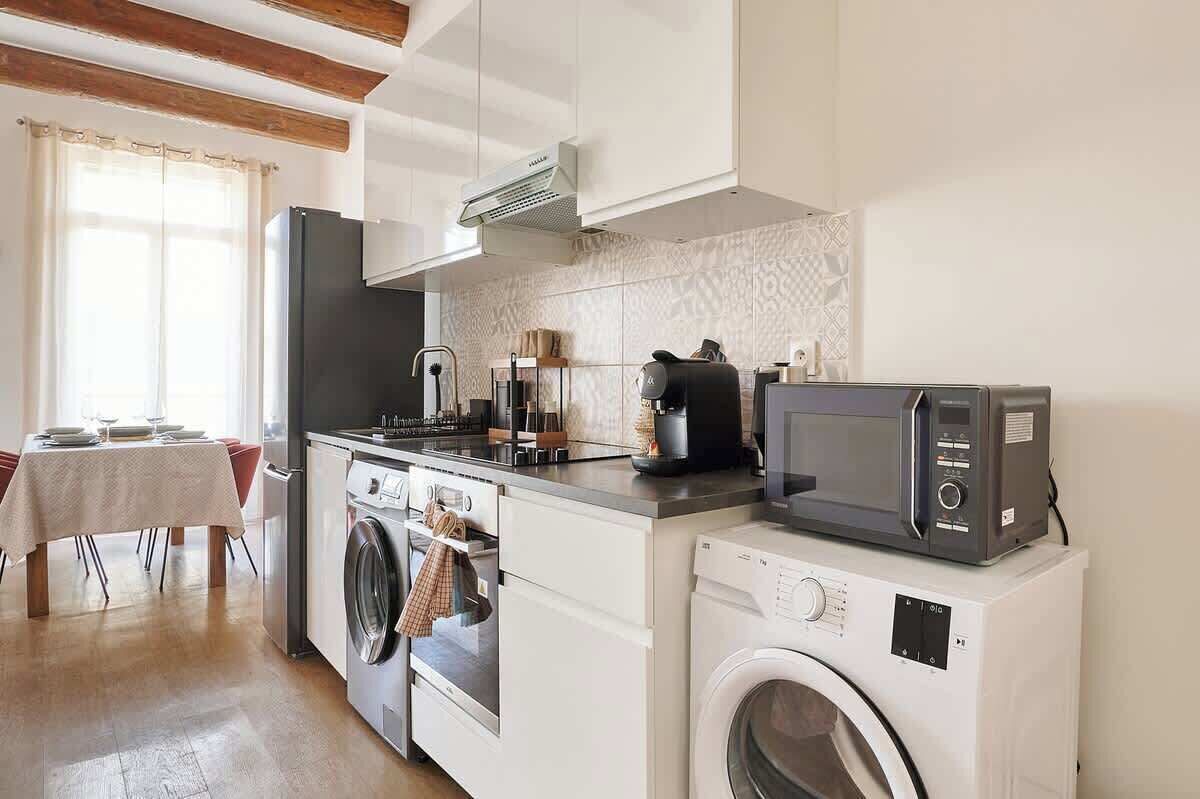 A compact kitchen with a washing machine, microwave, and a coffee maker.