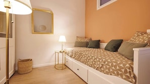 A bedroom with a bed, bedside lamp, and a small round table. - Le Chic face aux Halles clim  Classe 3 Etoiles (Béziers)