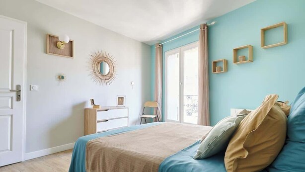 Un dormitorio con cama, cómoda, silla y ventana con cortinas.