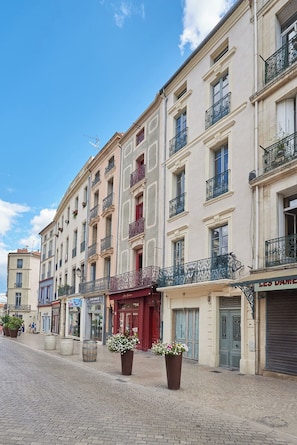A street with multi-story buildings, storefronts, and potted plants. - Cozy 1BR with A/C across les Halles (Tourcoing)