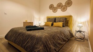 Una camera da letto con un letto grande, un comodino con una lampada e un punto luce a parete.