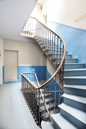 Eine Wendeltreppe mit Metallgeländer, die zu einer Zwischenebene mit einer Tür führt.