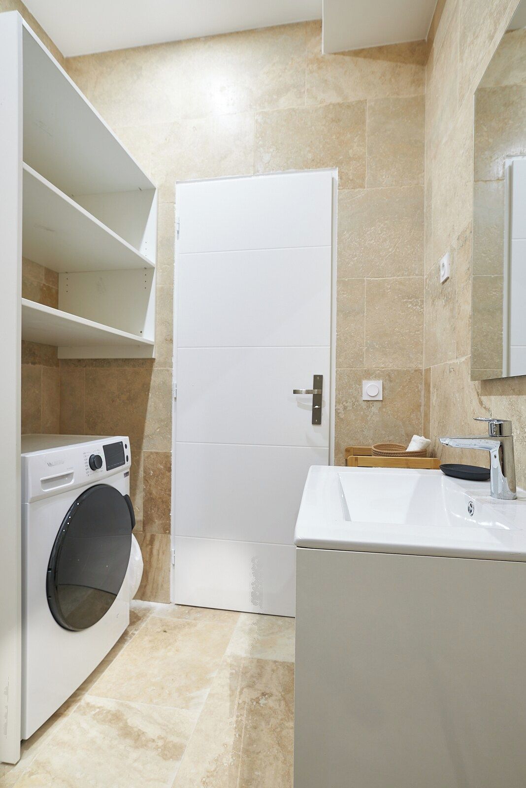 Een badkamer met een wasmachine, een wastafel en een spiegel.