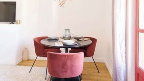 A dining area with a round table, red chairs, a vase, and a wall-mounted artwork. - MyLocTravel ✧ Central, facing Les Halles, AC (Béziers)