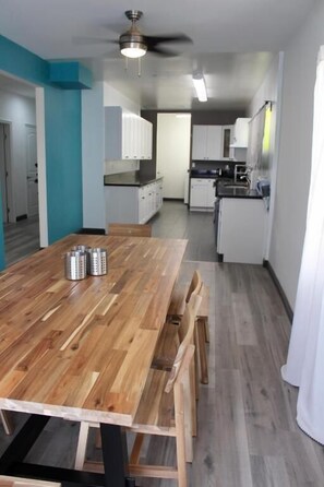 A modern kitchen with white cabinets, a wooden dining table, and a ceiling fan. - 8th & Ardmore  (Los Angeles)