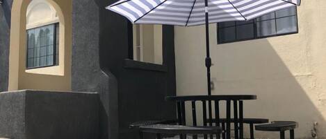 An outdoor seating area with a striped umbrella, a table, and chairs.