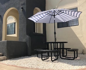 An outdoor seating area with a striped umbrella, a table, and chairs.