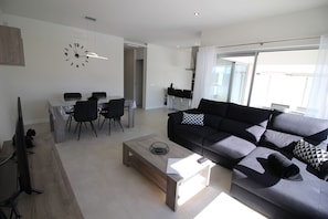 Ein modernes Wohnzimmer mit Sofa, Couchtisch und Essbereich.