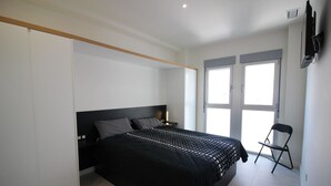 A bedroom with a bed, a chair, a TV, and a window. - Apartment Mirador de Villamartin (Orihuela)