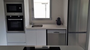 A compact kitchen with a built-in oven, a dishwasher, and a refrigerator. - Apartment Mirador de Villamartin (Orihuela)
