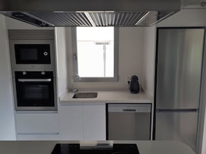 Eine kompakte Küche mit Einbauofen, Geschirrspüler und Kühlschrank.