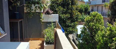 A balcony with a tiled floor, potted plants, and a white appliance.