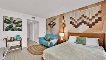 Ein Hotelzimmer mit Bett, Sofa, Nachttisch, Lampe und Wand mit geometrischem Muster.