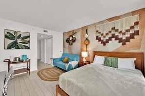 Ein Hotelzimmer mit Bett, Sofa, Nachttisch, Lampe und Wand mit geometrischem Muster.