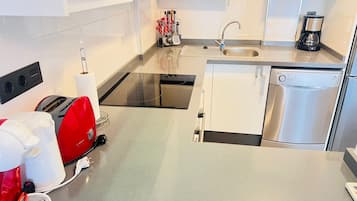 A modern kitchen with a dishwasher, a coffee maker, and a toaster.