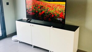Litteänäyttöinen televisio on sijoitettu valkoiseen kaappiin, ja sen näytöllä näkyy punaisia kukkia.
