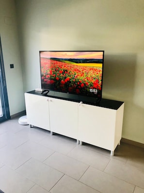 A flat-screen TV on a white cabinet with a field of red flowers on the screen. - Penthouse Oasis Beach II la Zenia (Orihuela)