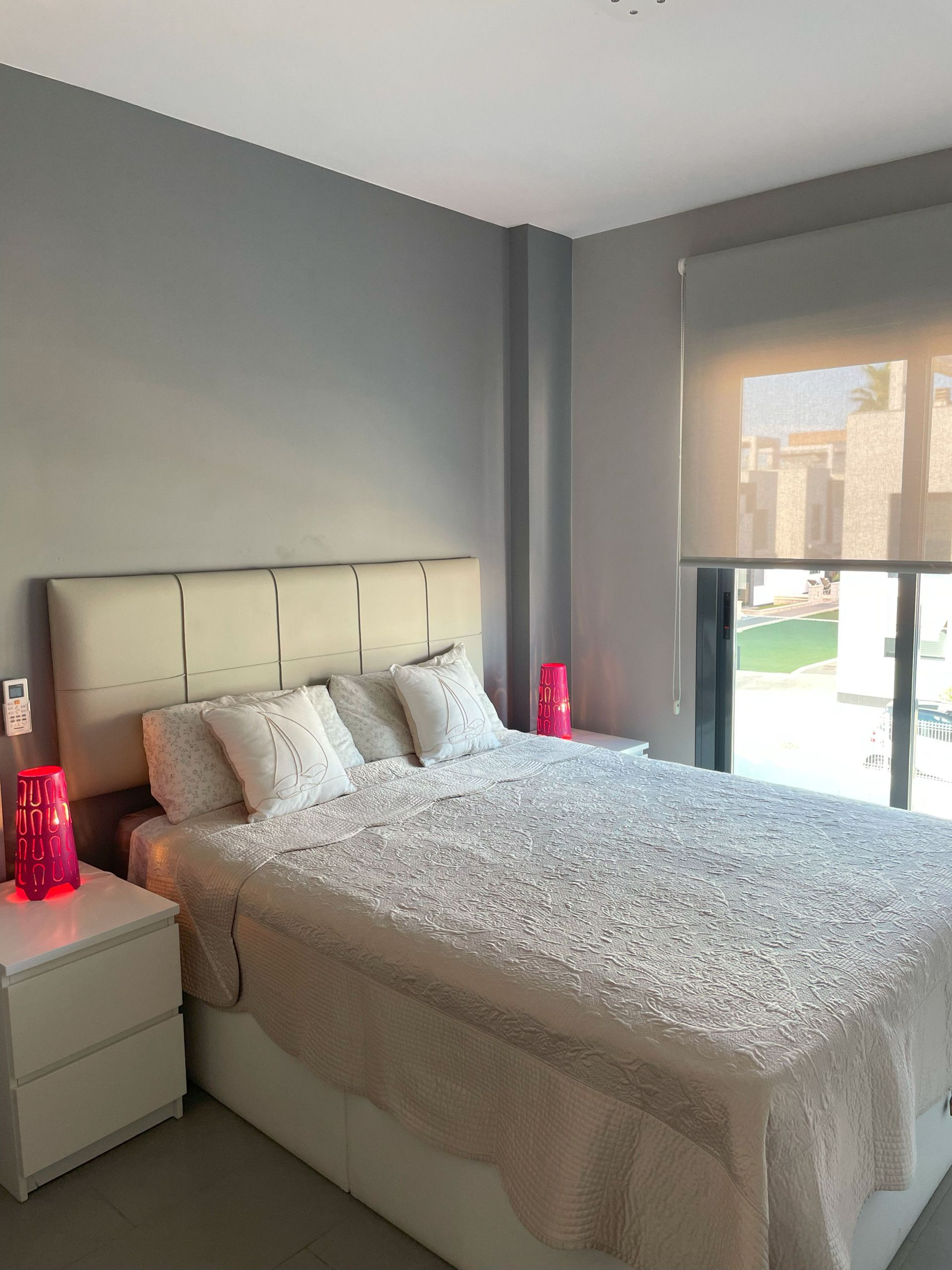 Un dormitorio moderno con una cama grande, dos mesitas de noche y una ventana con vistas al exterior.