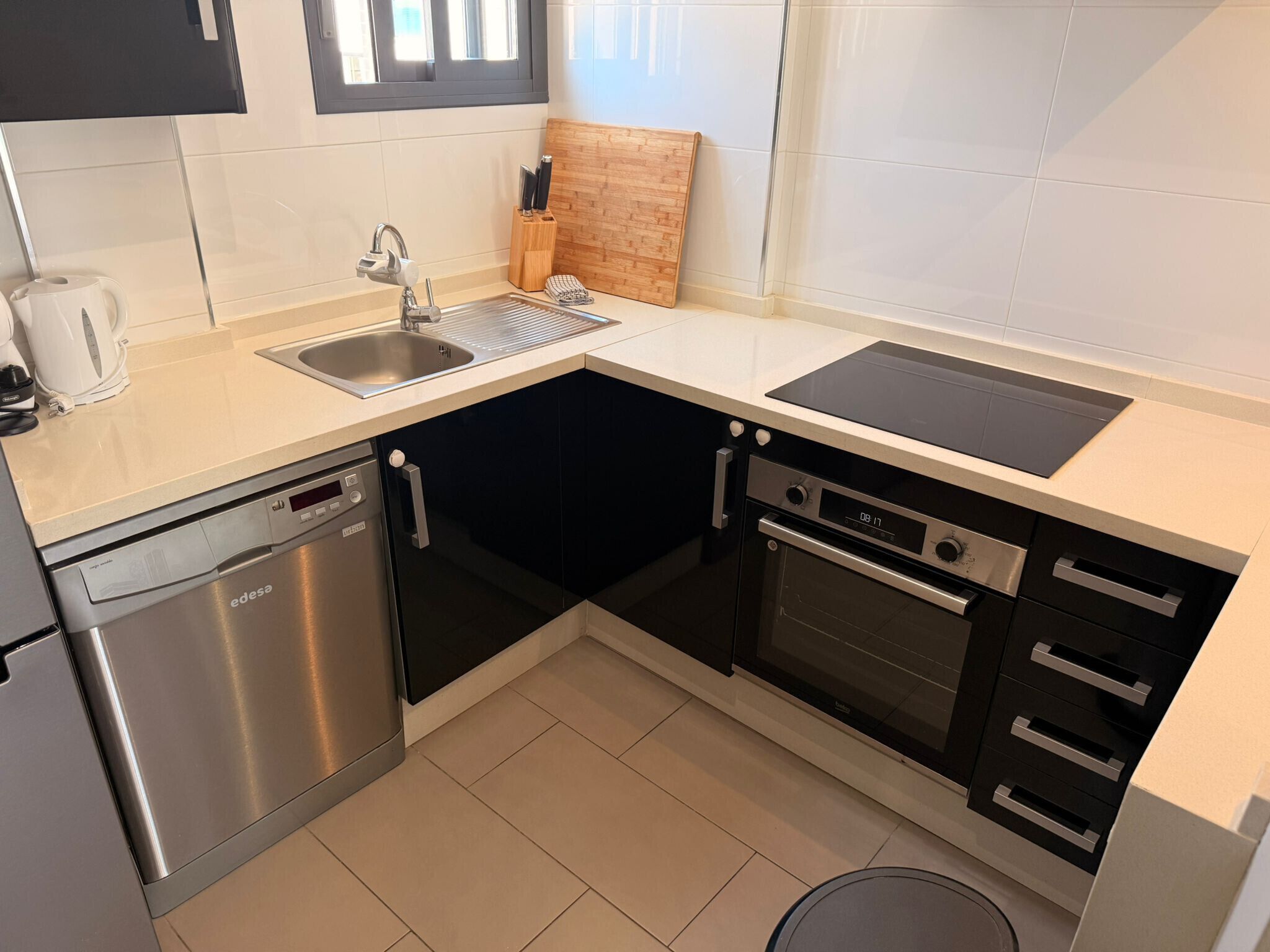 Een kleine keuken met een vaatwasser, oven en spoelbak.