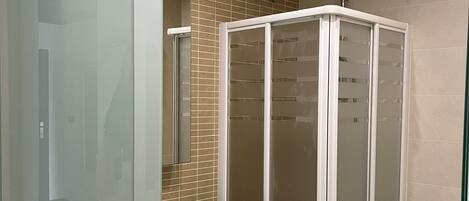 A bathroom with a glass-enclosed shower, a white sink, and a toilet.