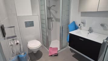 Une salle de bain moderne dotée d’une douche à parois de verre, de toilettes et d’un lavabo avec un meuble noir.