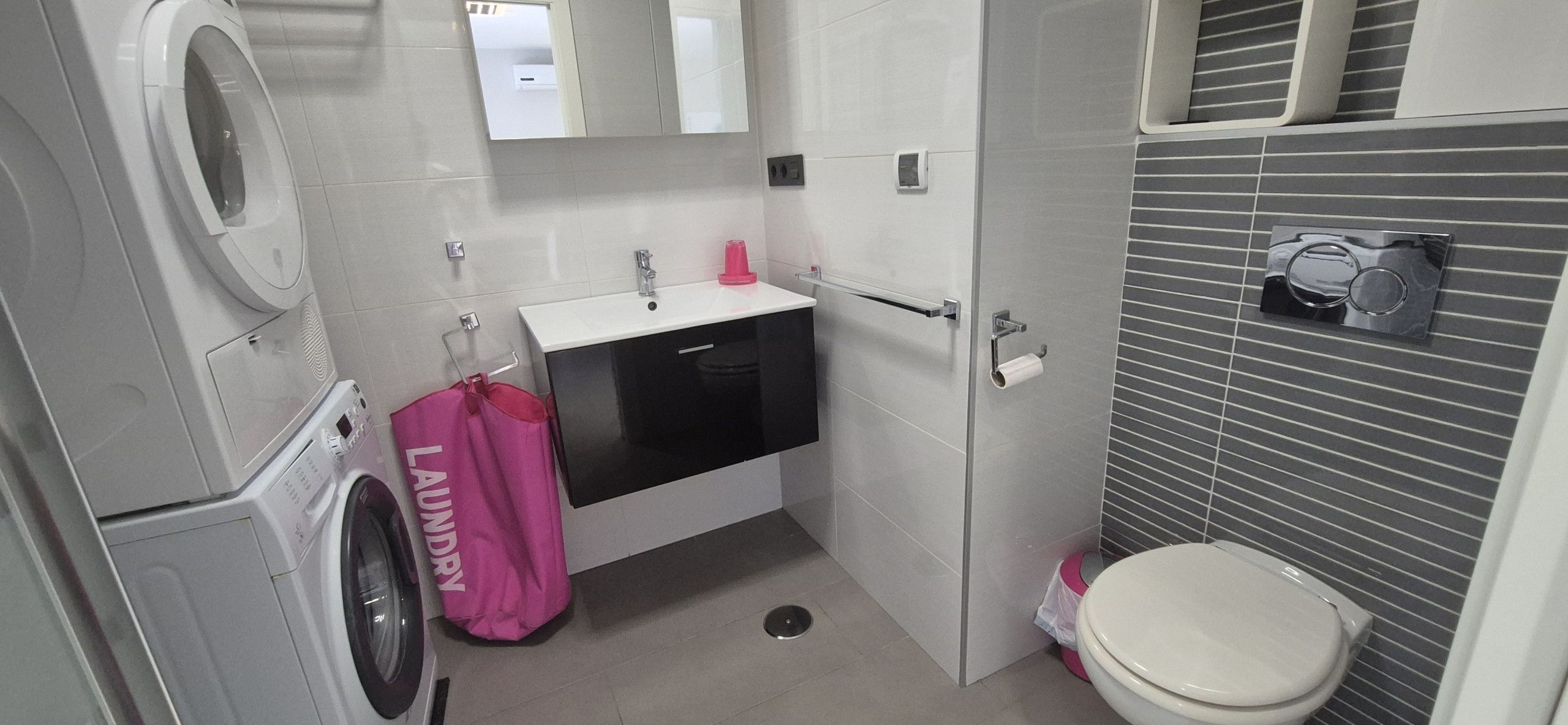 Un baño pequeño con lavadora, lavamanos y retrete.