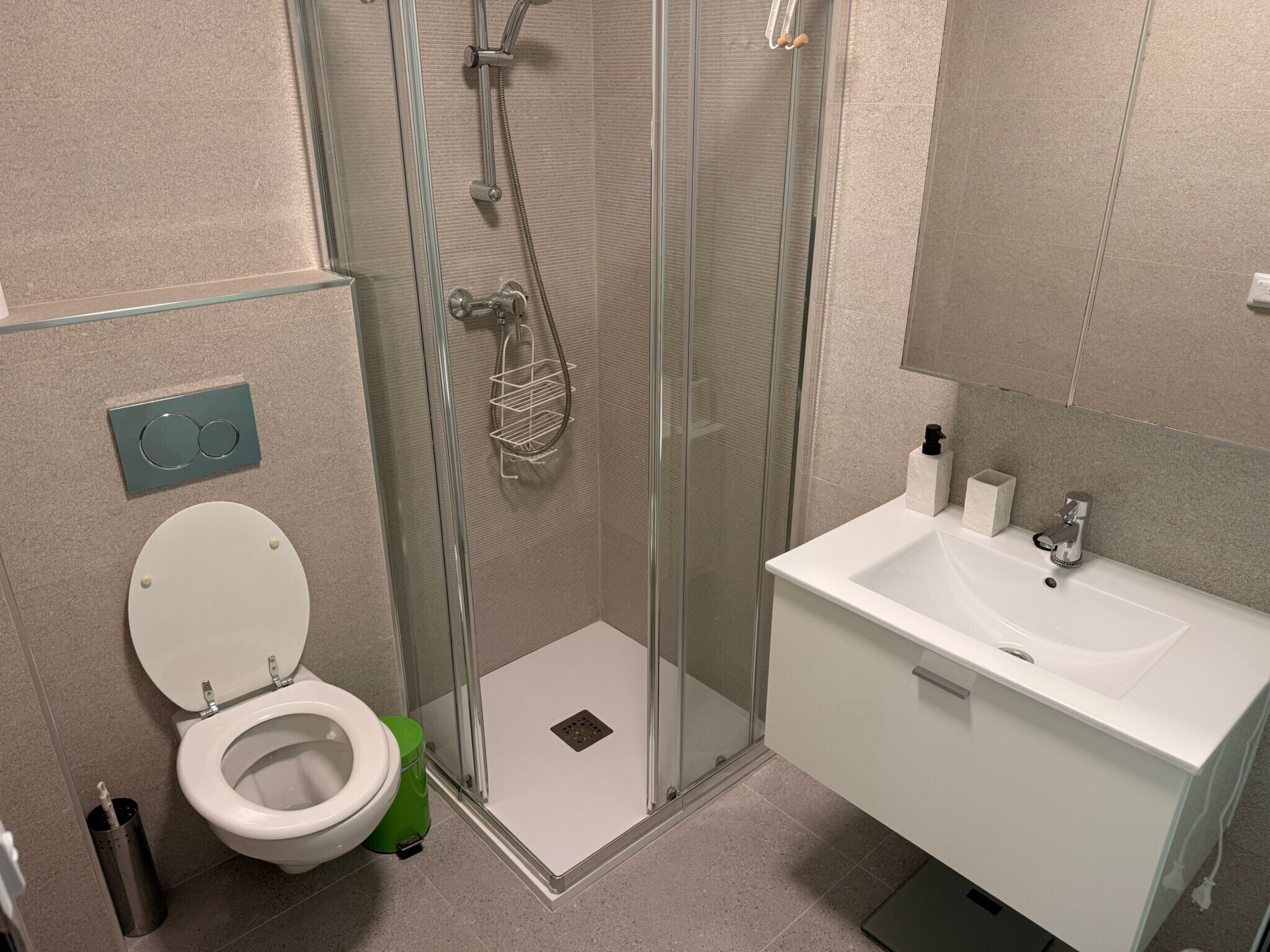 Une salle de bain avec une douche à parois de verre, un lavabo blanc et des toilettes.