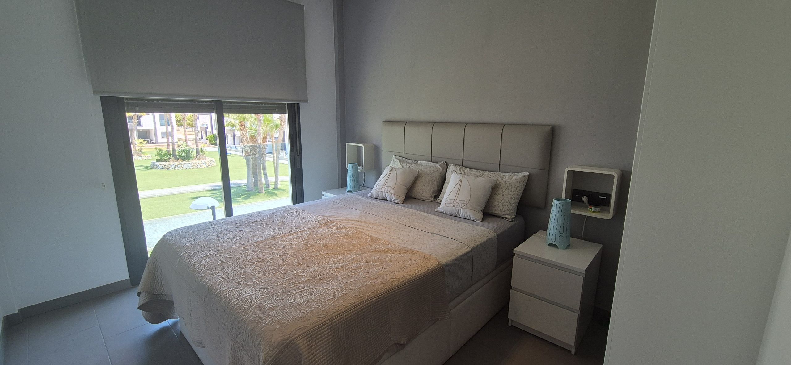 Un dormitorio con una cama grande, una mesita de noche y un ventanal con vistas a un jardín.