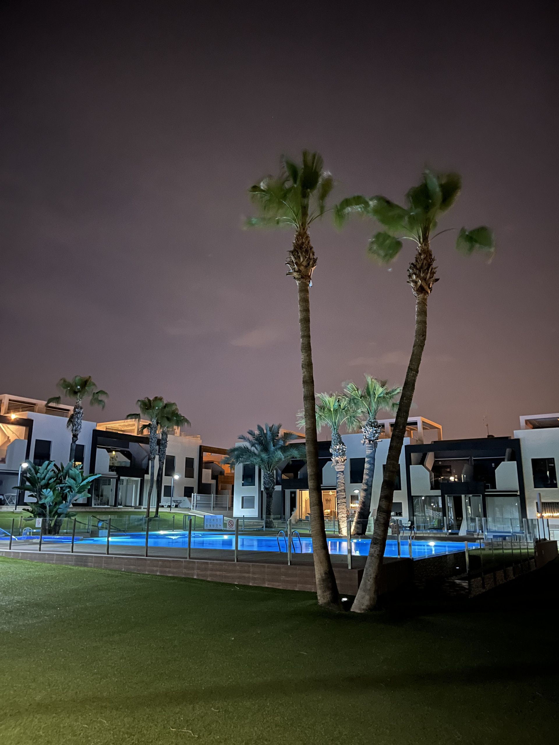 Um hotel moderno com piscina, palmeiras e arquitetura contemporânea.