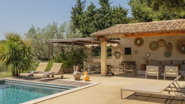 A poolside area with lounge chairs, a small pool, and a covered seating area with decorative wall art.