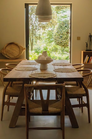Una mesa de comedor con individuales tejidos, sillas de madera y una lámpara colgante.
