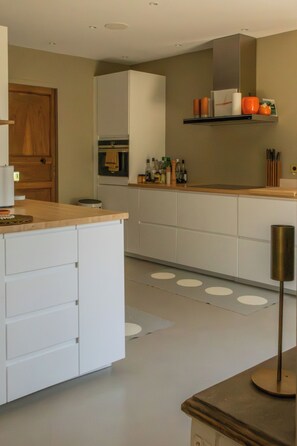 Une cuisine moderne avec des meubles blancs, un plan de travail en bois et un four encastré.