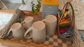 A tray with four grey mugs, a yellow container labeled 'MON INDISPENSABLE BOITE,' and a basket of colorful pencils.