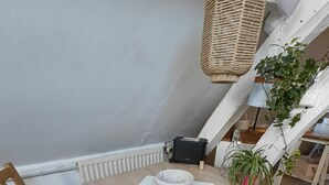 Een houten eettafel met twee stoelen, een mand en een kleine tafellamp.