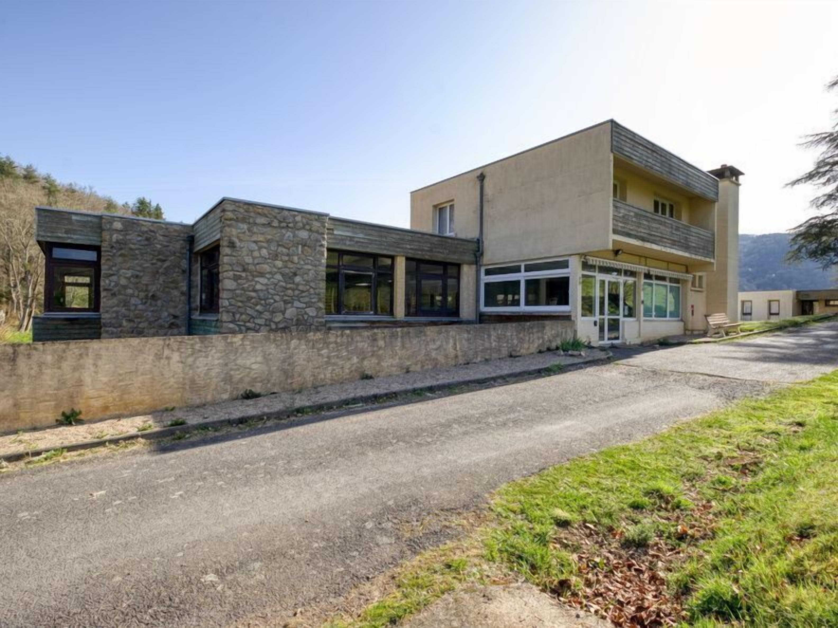 A modern two-story building with a stone facade and large windows.