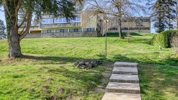 A grassy area with a stone staircase leading up to a building with a stone facade and windows.