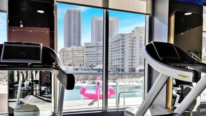 Una palestra con attrezzature sportive e vista sulla città attraverso ampie finestre.