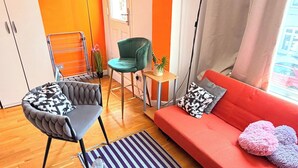 A modern living room with a sofa, armchair, and a small table with a plant. - Apartment Sleeps 8 in Fulham-chelsea (London)