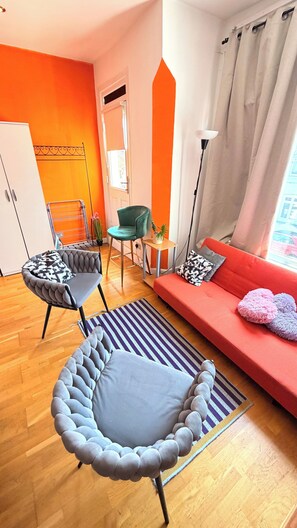 A modern living room with a sofa, armchair, and a small table with a plant. - Apartment Sleeps 8 in Fulham-chelsea (London)