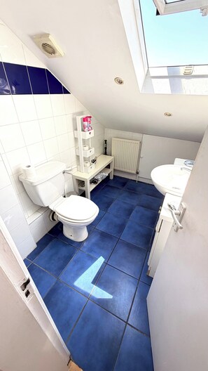 A small bathroom with a toilet, sink, and a radiator. - Apartment Sleeps 8 in Fulham-chelsea (London)