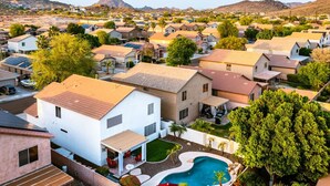 Un barrio residencial con casas, una piscina y una montaña al fondo.