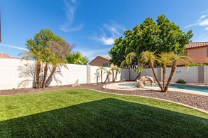A backyard with a swimming pool, palm trees, a white brick wall, and a well-maintained lawn. - Sleek 5bed pet friendly & pool (Peoria)