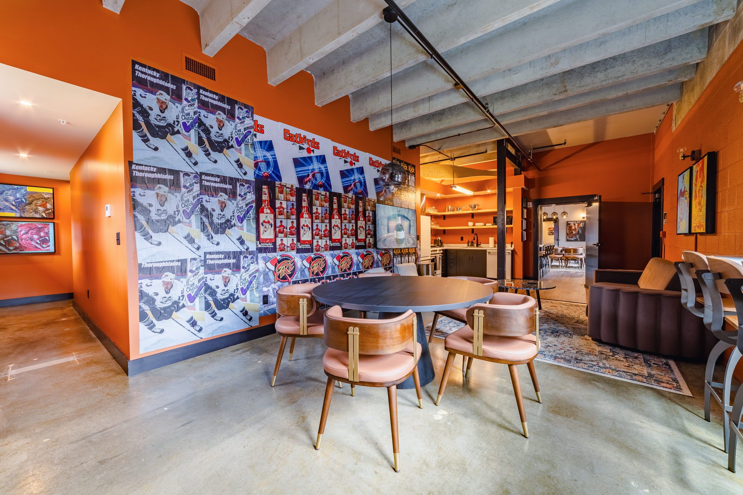 A spacious room with a large round table, multiple chairs, and a wall adorned with sports memorabilia.