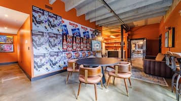 A spacious room with a large round table, multiple chairs, and a wall adorned with sports memorabilia.