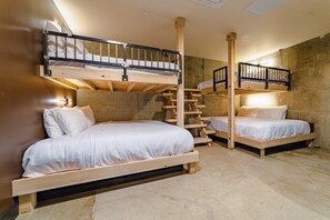 Una habitación con dos literas, una escalera de madera y una pared de concreto.