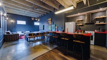 A modern kitchen with a bar area, wooden bar stools, and a dining table with chairs.